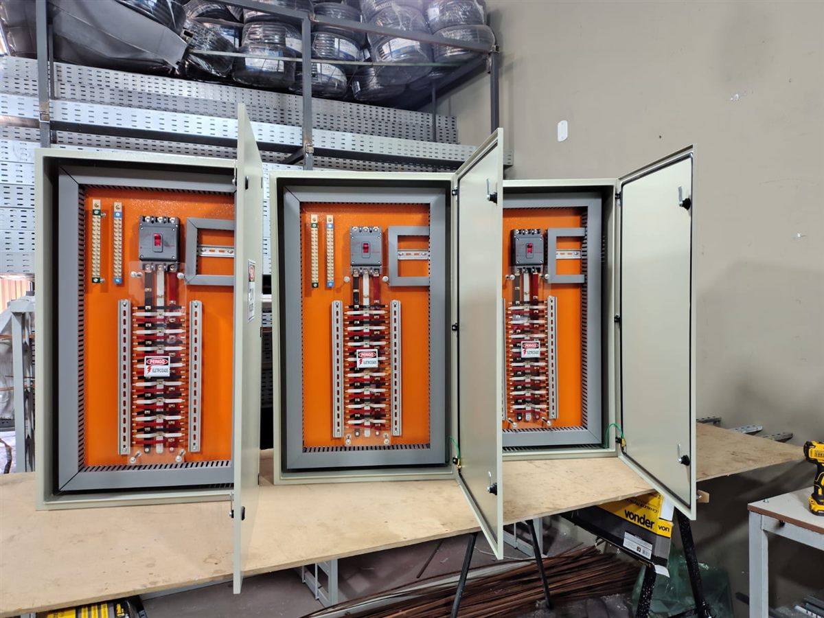 Três quadros de distribuição abertos com placa de montagem laranja