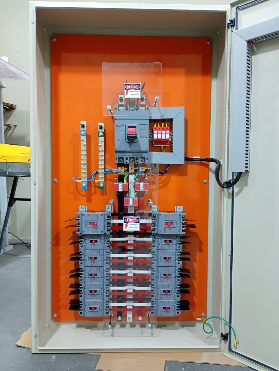 Quadro de distribuição com placa laranja, disjuntor geral e barramento